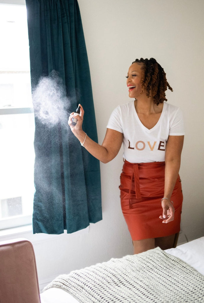 Model in Orange leather Skirt and Love Tee spraying Mist spray in the air and on curtains